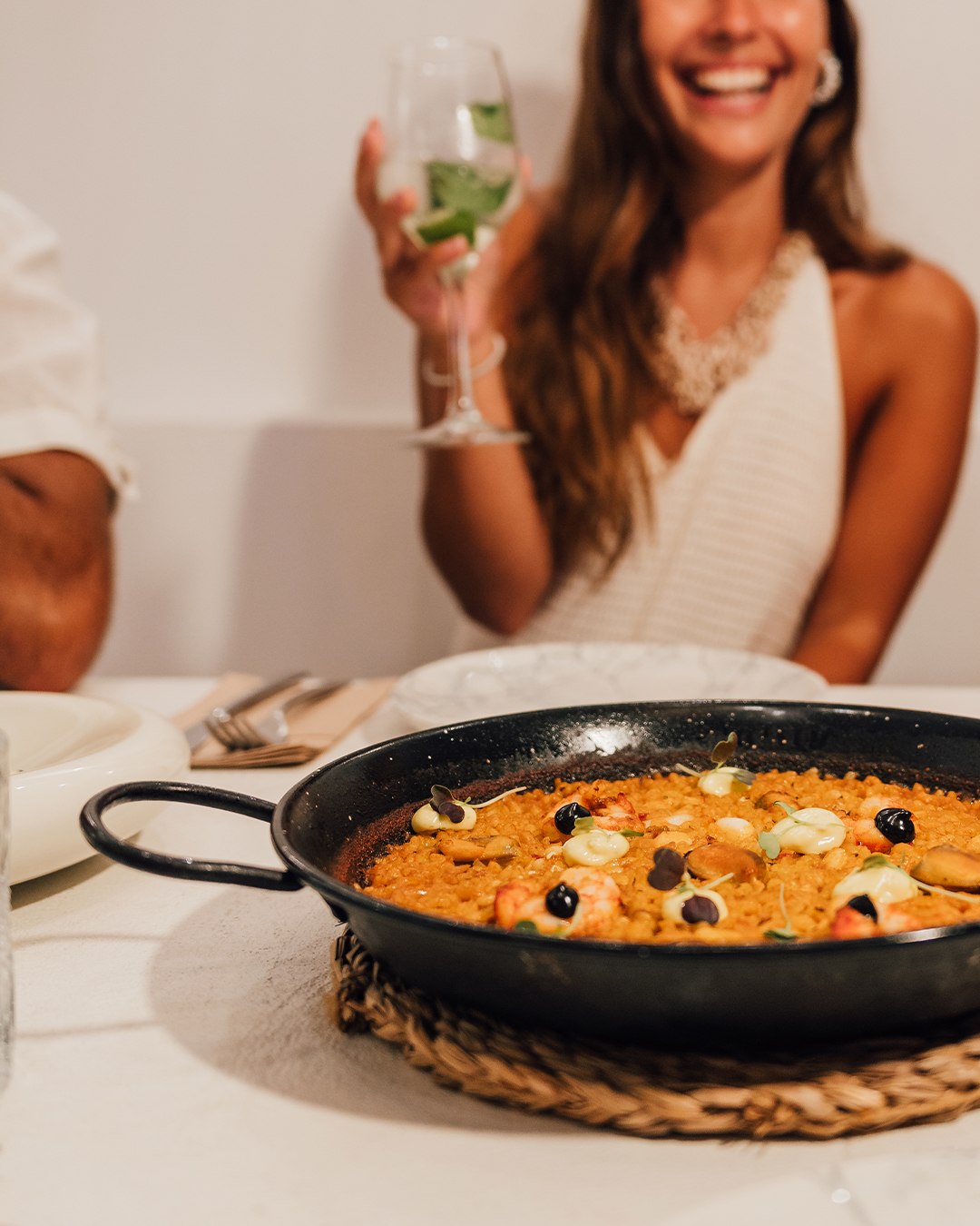 Paella de arroz con marisco recién hecha, con una copa de vino en primer plano